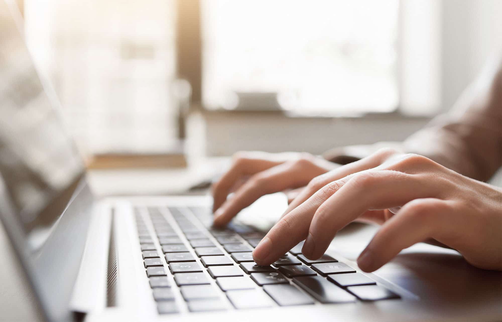 Typing on laptop closeup, chatting in Facebook